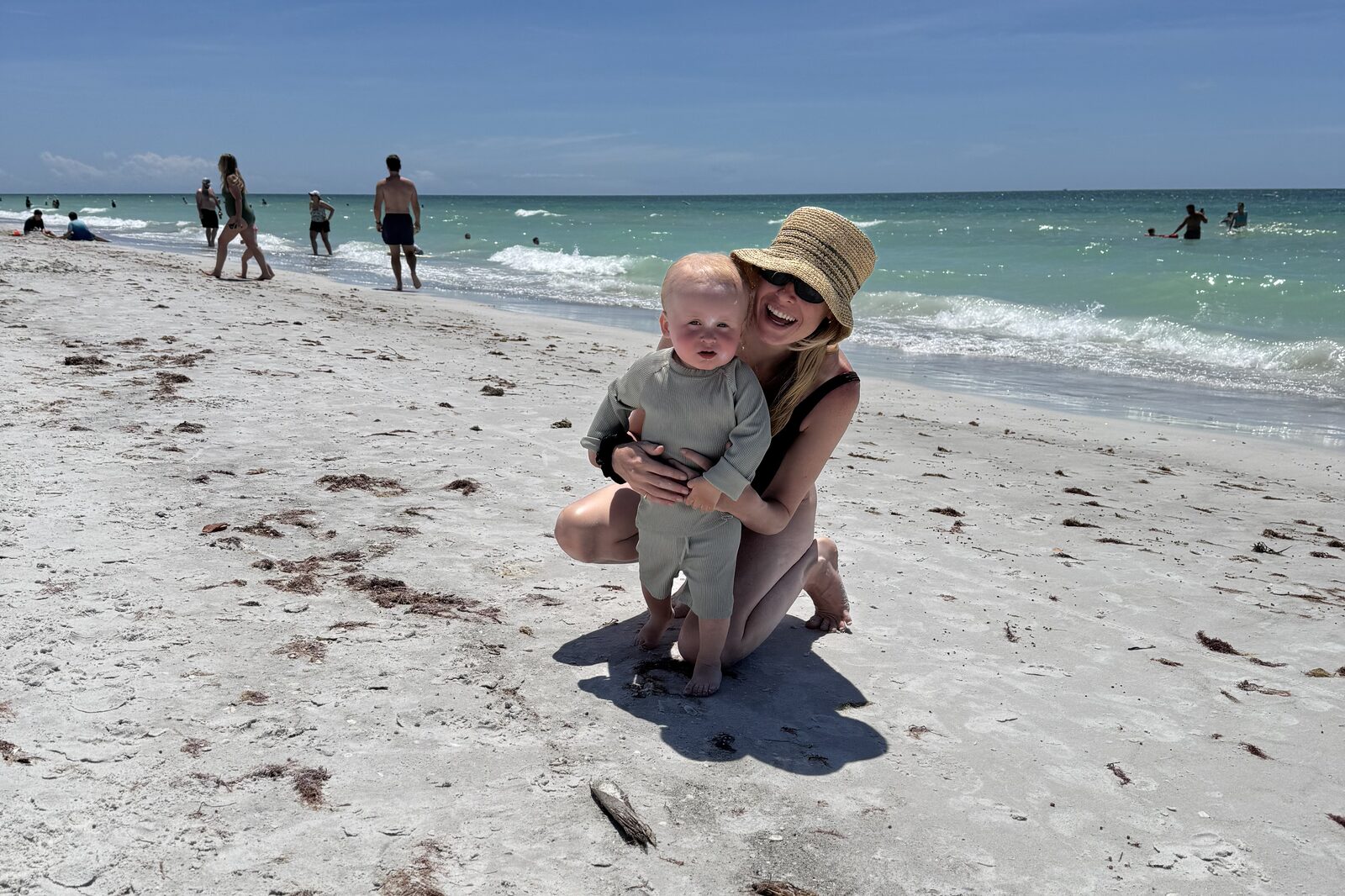 A mum laughing on the beach with her baby
